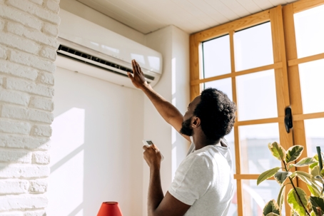 young man turning on air conditioner
